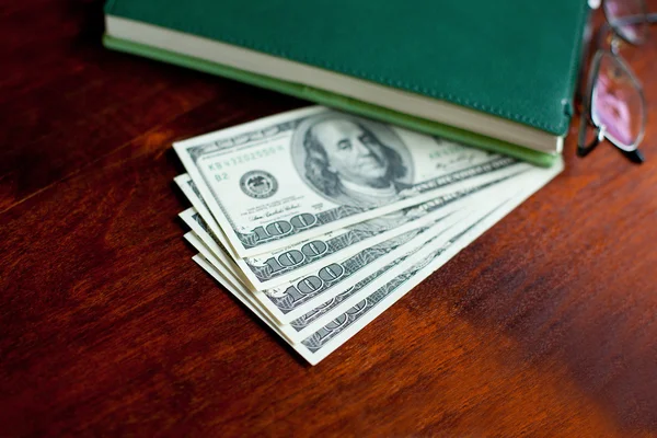 Stacks of one hundred dollars banknotes in notebook