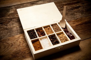 Assortment of spices in wooden box on old wooden table clipart