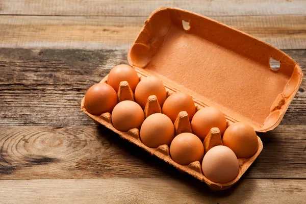 Яйца в упаковке на деревянном столе — стоковое фото