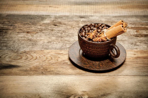 Holztasse mit Kaffeebohnen auf Holztisch — Stockfoto