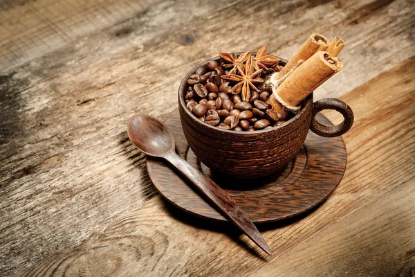 Holztasse mit Kaffeebohnen auf Holztisch — Stockfoto