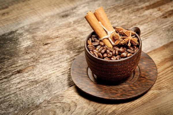 Houten kop met koffiebonen op houten tafel — Stockfoto