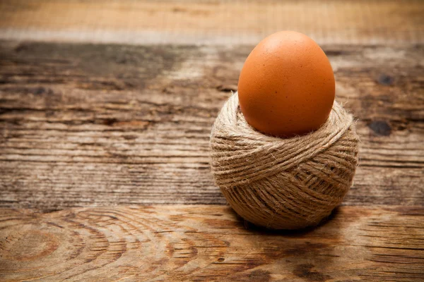 Uovo in bobina di corda su vecchio tavolo di legno — Foto Stock