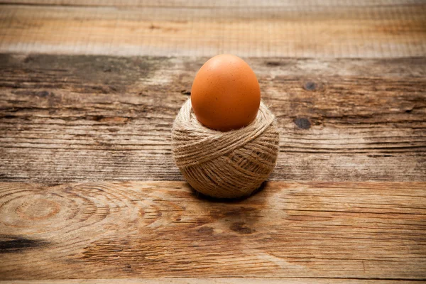 Uovo in bobina di corda su vecchio tavolo di legno — Foto Stock