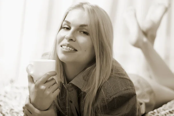 Woman lying at the bed and drinking coffee. — Stock Photo, Image