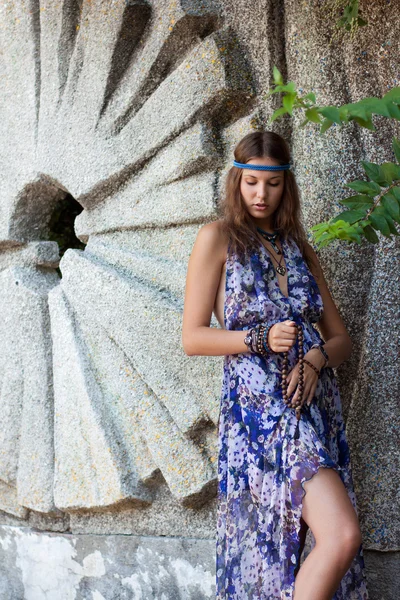 Vrouw in een sundress op de stenen muur — Stockfoto