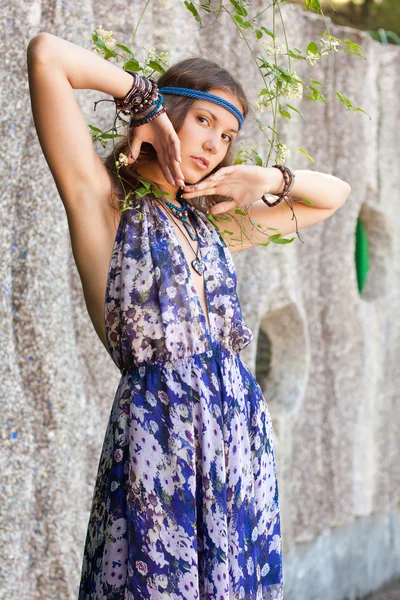 Mulher em um vestido de verão na parede de pedra — Fotografia de Stock