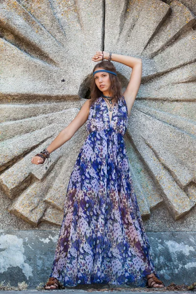 Vrouw in een sundress op de stenen muur — Stockfoto