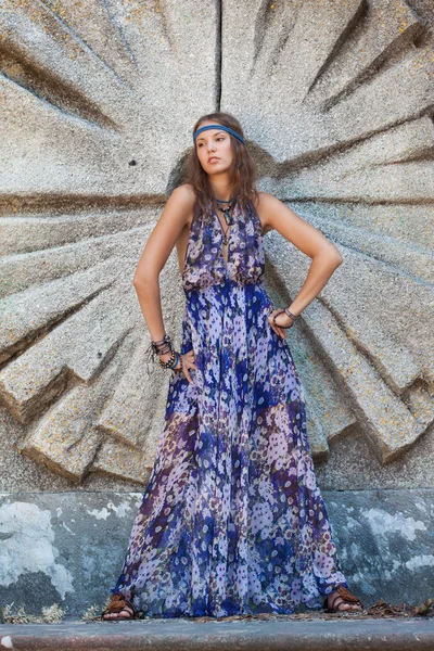 Mulher em um vestido de verão na parede de pedra — Fotografia de Stock