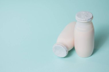 Probiyotik ve prebiyotik süt ürünleri içeren şişeler açık mavi arka planda. Kullanışlı mikroorganizmalı biyo-yoğurt. Biyolojik olarak aktif katkı maddeleri üretimi. Fermantasyon ve diyet sağlıklı yiyecekler.