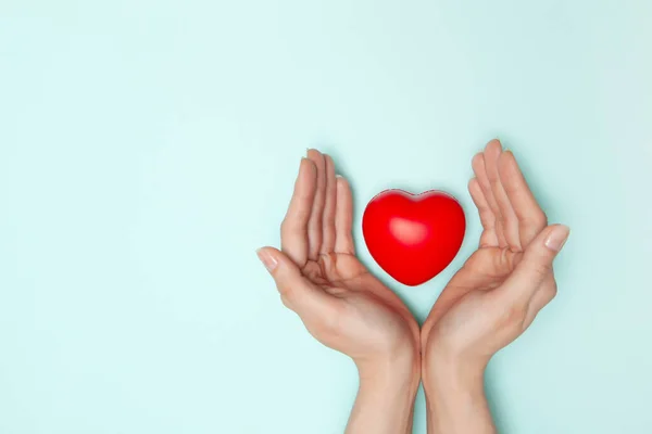 Health, medicine and charity concept - close up of female hands with small red heart — Stock Photo, Image