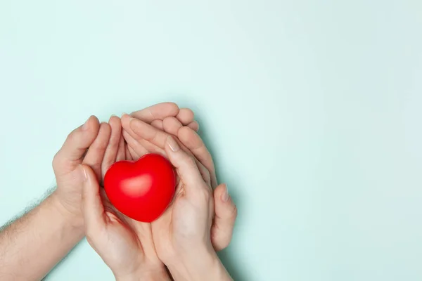 Homme et femme mains tenant coeur rouge, soins de santé, don et concept d'assurance familiale, journée mondiale du cœur. — Photo