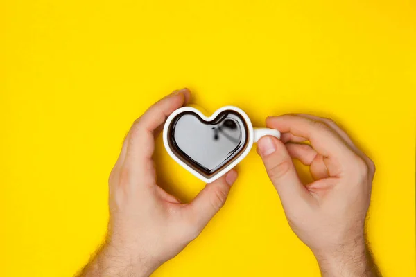 Les mains de l'homme tient tasse de café en forme de coeur. — Photo