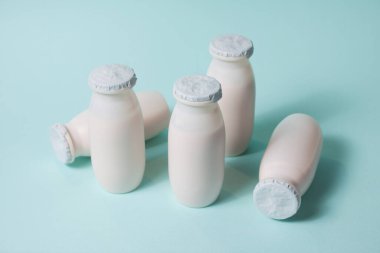 Probiyotik ve prebiyotik süt ürünleri içeren şişeler açık mavi arka planda. Kullanışlı mikroorganizmalı biyo-yoğurt. Biyolojik olarak aktif katkı maddeleri üretimi. Fermantasyon ve diyet sağlıklı yiyecekler.