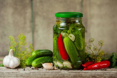 Ahşap arka planda turşu hazırlamak için cam kavanozlarda, baharatlarda ve sebzelerde salatalık turşusu..