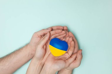 Ukrayna 'nın ulusal bayrağını kadın ve erkeğin ellerine basan kalp. Düz yatıyordu.