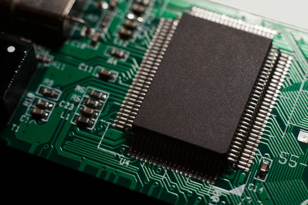 Macro photo of a green computer printed circuit board with selective focus on an blank chip — Stock Photo, Image