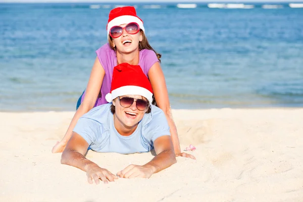 Nádherný pár v santa klobouky na tropické pláži bali — Stock fotografie