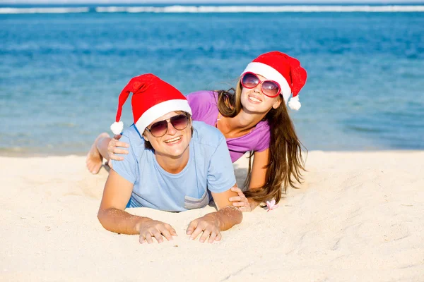Bella coppia in cappelli di Babbo Natale sulla spiaggia tropicale di Bali — Foto Stock