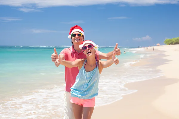 Casal jovem em chapéus de santa rindo na praia tropical. ano novo — Fotografia de Stock