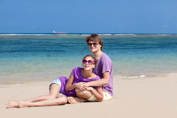 美しい若いカップルと楽しいビーチに座っています。 — ストック写真