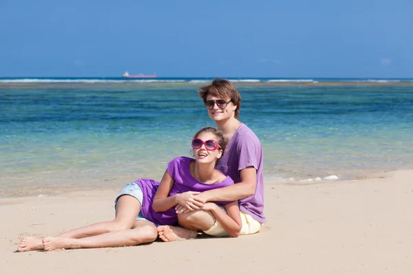 Bonito jovem casal sentado e se divertindo na praia — Fotografia de Stock