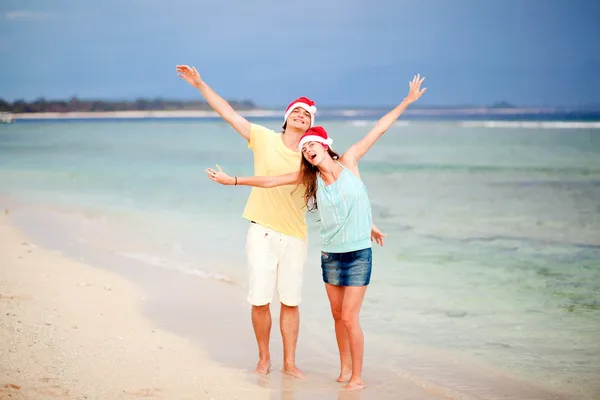 Νεαρό ζευγάρι στην καπέλα santa γέλιο σε τροπική παραλία. νέο έτος — Φωτογραφία Αρχείου