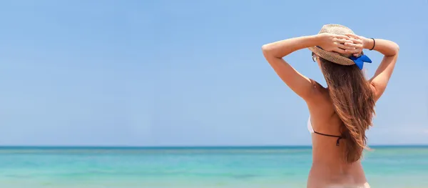 年轻女子在热带海滩看比基尼和秸秆帽子 — 图库照片