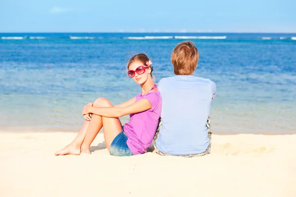 Krásný mladý pár sedí a baví na pláži — Stock fotografie