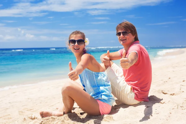 Beautiful young couple sitting and having fun on beach — Stock Photo, Image