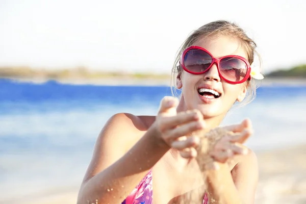 Mujer atractiva tamizando arena a través de las manos en la playa tropical — Foto de Stock