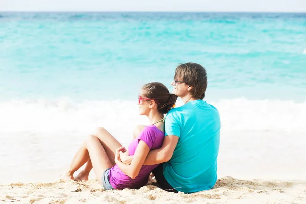 Bonito jovem casal sentado e se divertindo na praia — Fotografia de Stock