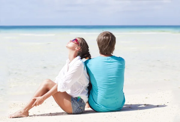 Bonito jovem casal sentado e se divertindo na praia — Fotografia de Stock