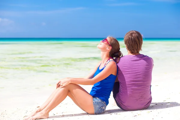 Schönes junges Paar sitzt und Spaß am Strand hat Stockfoto