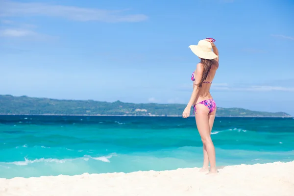 美しい若い女性は、太陽を楽しんでビーチに立っています。 — ストック写真