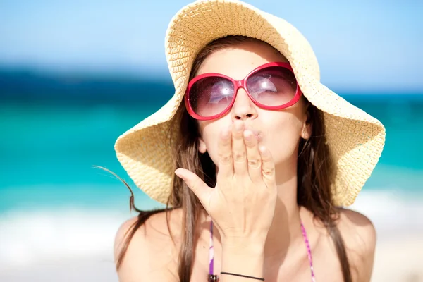 Playa Retrato de mujer joven en gafas de sol y sombrero soplando beso —  Fotos de Stock