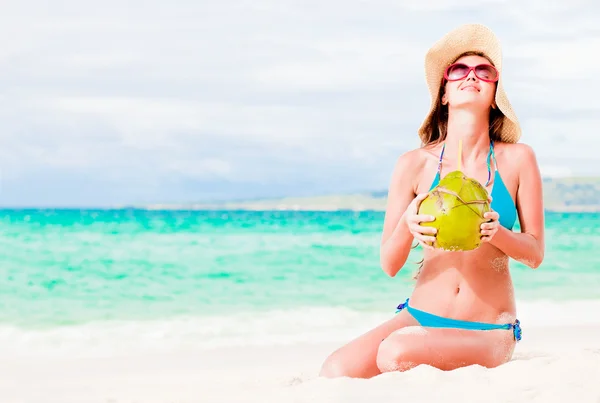 Smiling young woman in straw hat with coconut on the beach — Stock Photo, Image