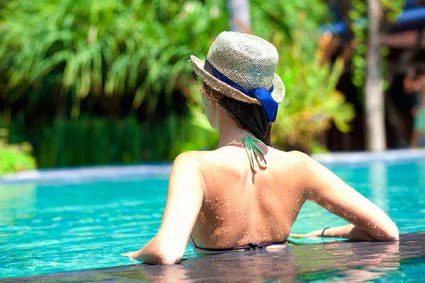 Vista trasera de hermosa mujer en sombrero de paja en piscina de lujo — Foto de Stock