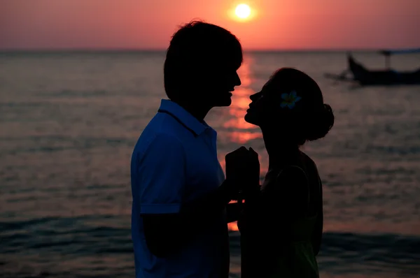 Romántica joven pareja silueta puesta del sol en la playa. luna de miel — Foto de Stock