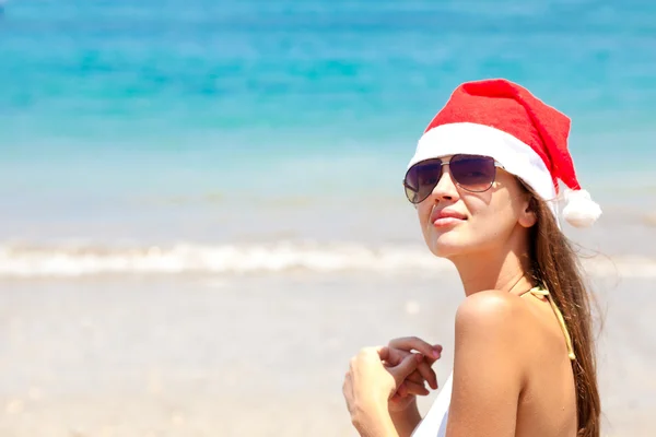 Portret pięknej młodej kobiety w santa hat na tropikalnej plaży — Zdjęcie stockowe