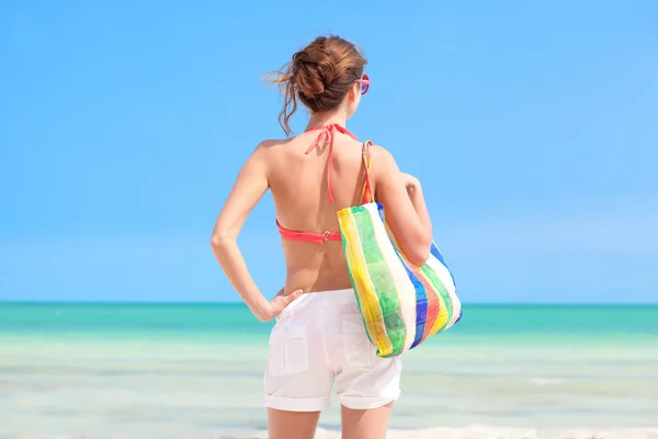 Widok kobiety w bikini z torba plażowa i Słomkowy kapelusz z tyłu — Zdjęcie stockowe