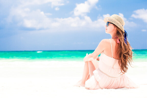 Back view of woman in straw hat and dress on tropical beach