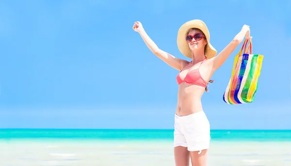 Mujer en sombrero de paja y bikini con bolsa de playa disfrutando de sus vacaciones — Foto de Stock