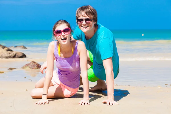 Primer plano de feliz pareja joven en gafas de sol sentado en la playa sonriendo —  Fotos de Stock