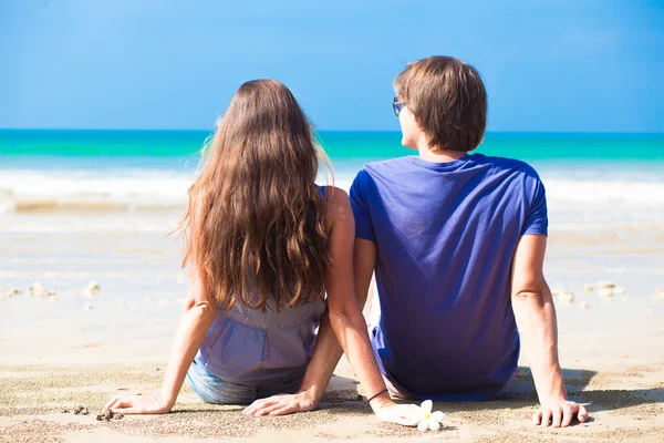 Jeune couple heureux assis sur la plage tropicale — Photo