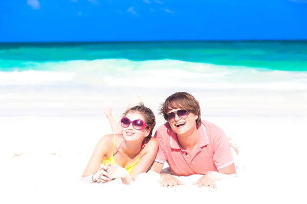 Gros plan de heureux jeune couple dans des lunettes de soleil couché sur la plage souriant — Photo