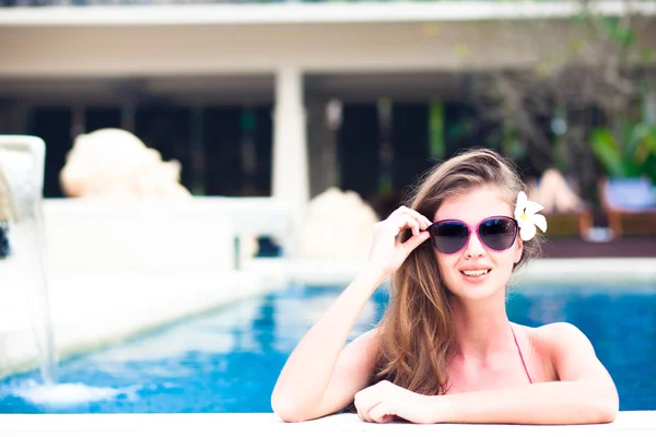 Ritratto di giovane attraente donna sorridente con fiore in capelli in piscina di lusso — Foto Stock