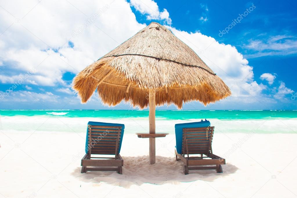 Chairs and umbrella on white sand beach in Tulum