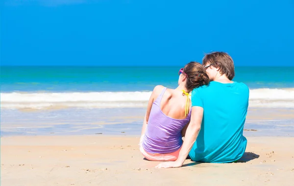 Пара сидящих на тропическом пляже — стоковое фото
