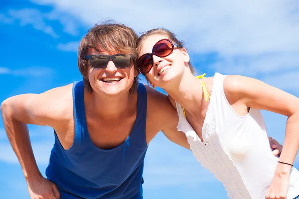 Closeup of happy young couple in sunglasses smiling on tropical beach — Stock Photo, Image